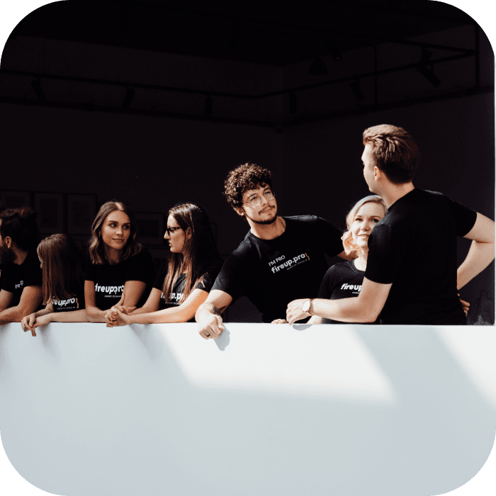 Czarno białe tło i część zespołu fireup.pro - copywriter, graficzka, developerzy i inżynierowie IT rozmawiają z Employer Branding Area Leader.