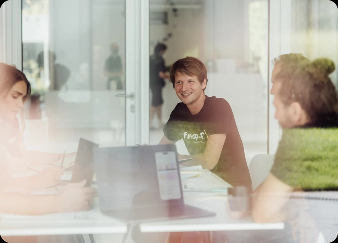 W 4 osobowym zespole omawiamy migrację do chmury, jeden z procesów przeprowadzanych dla naszego klienta. Spotkanie odbywa się we współczesnym biurze a notatki zapisujemy na laptopach, by podzielić się wnioskami z programistami fireup.pro