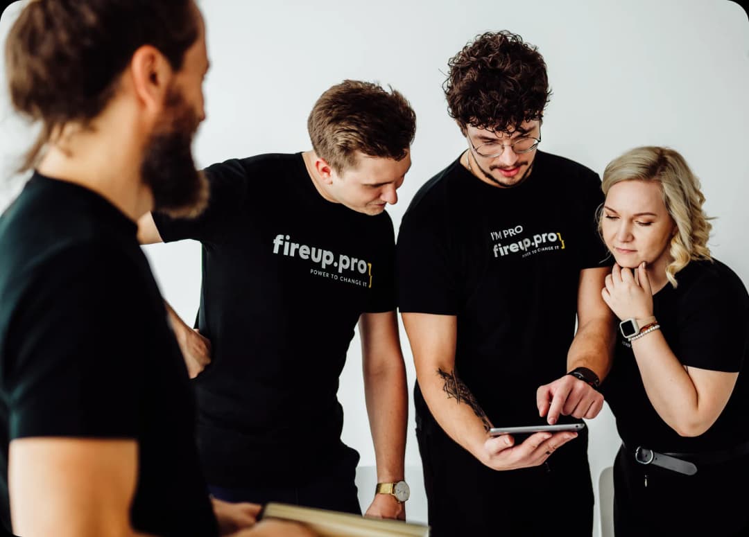 Na tablecie jeden z naszych developerów przestawia swoje pomysły dotyczące migracji danych pozostałej 3 zespołu. Wspólnie omawiają fazy projektu oraz to jakich technologii powinniśmy użyć, by spełnić wymagania biznesowe klienta. A to wszystko w czarnych, firmowych t-shirtach.